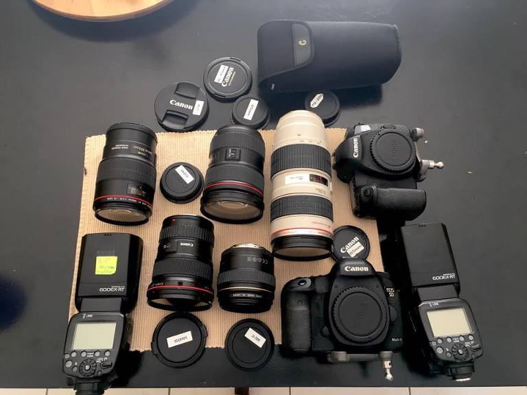 table full of various canon lenses and flashes